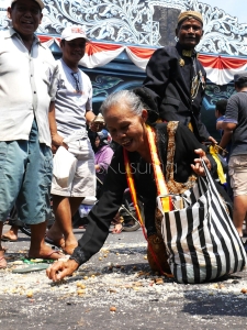 Seorang wanita bersemangat mengumpulkan remah gunungan dalam acara Gerebeg Syawal di depan Keraton Kasunanan Surakarta, Jawa Tengah. Acara ini menjadi salah satu acara yang diminati wisatawan setiap tahun.